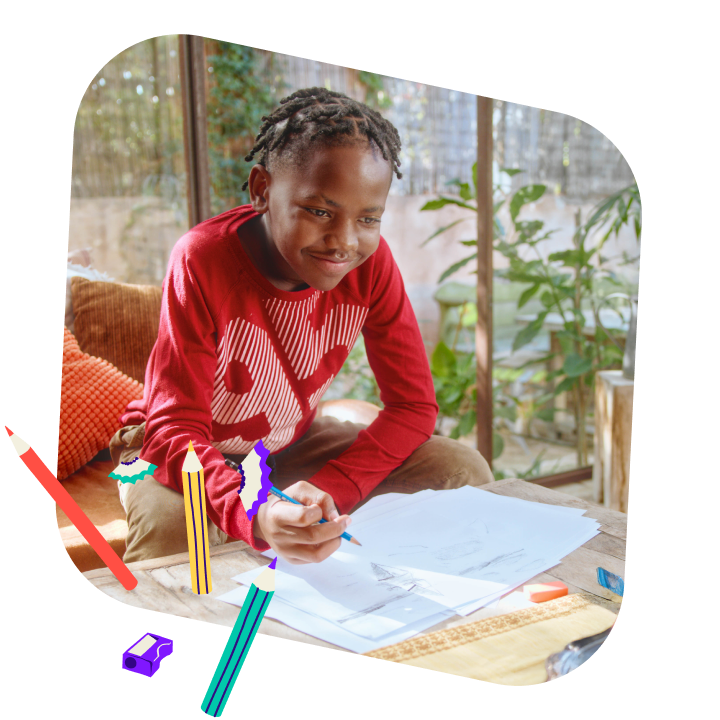 A child drawing, surrounded by colorful pencils and a pencil sharpener