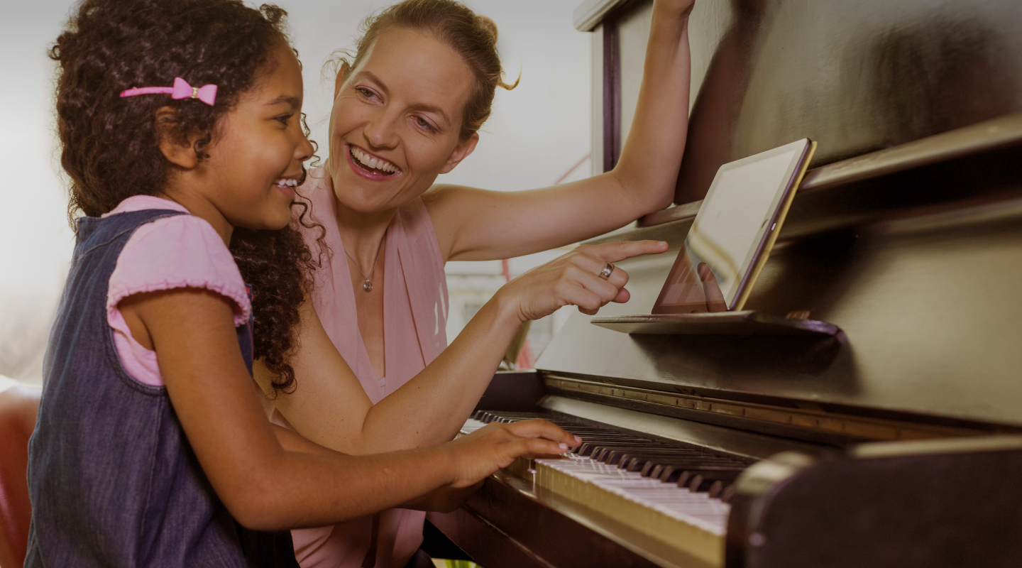 A teacher and a young girl playing piano